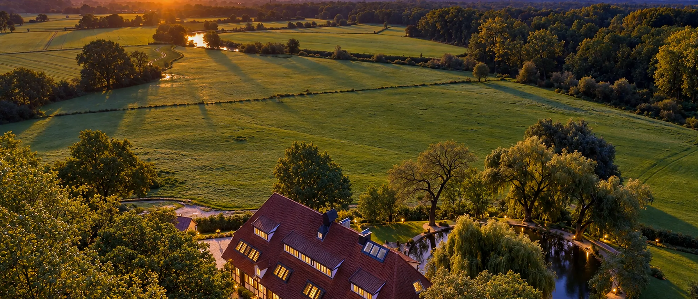 Luftbild der Schlossresidenz im Park, Wiesen und Teich im Abendlicht
